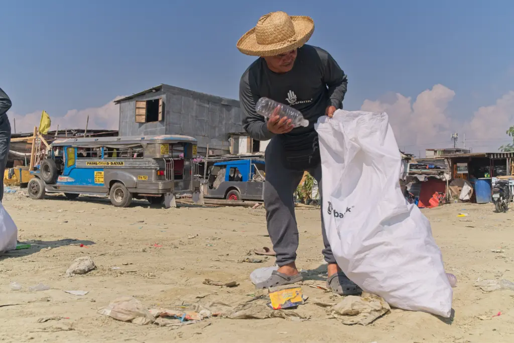 A Plastic Bank collector picking up plastic trash for recycling